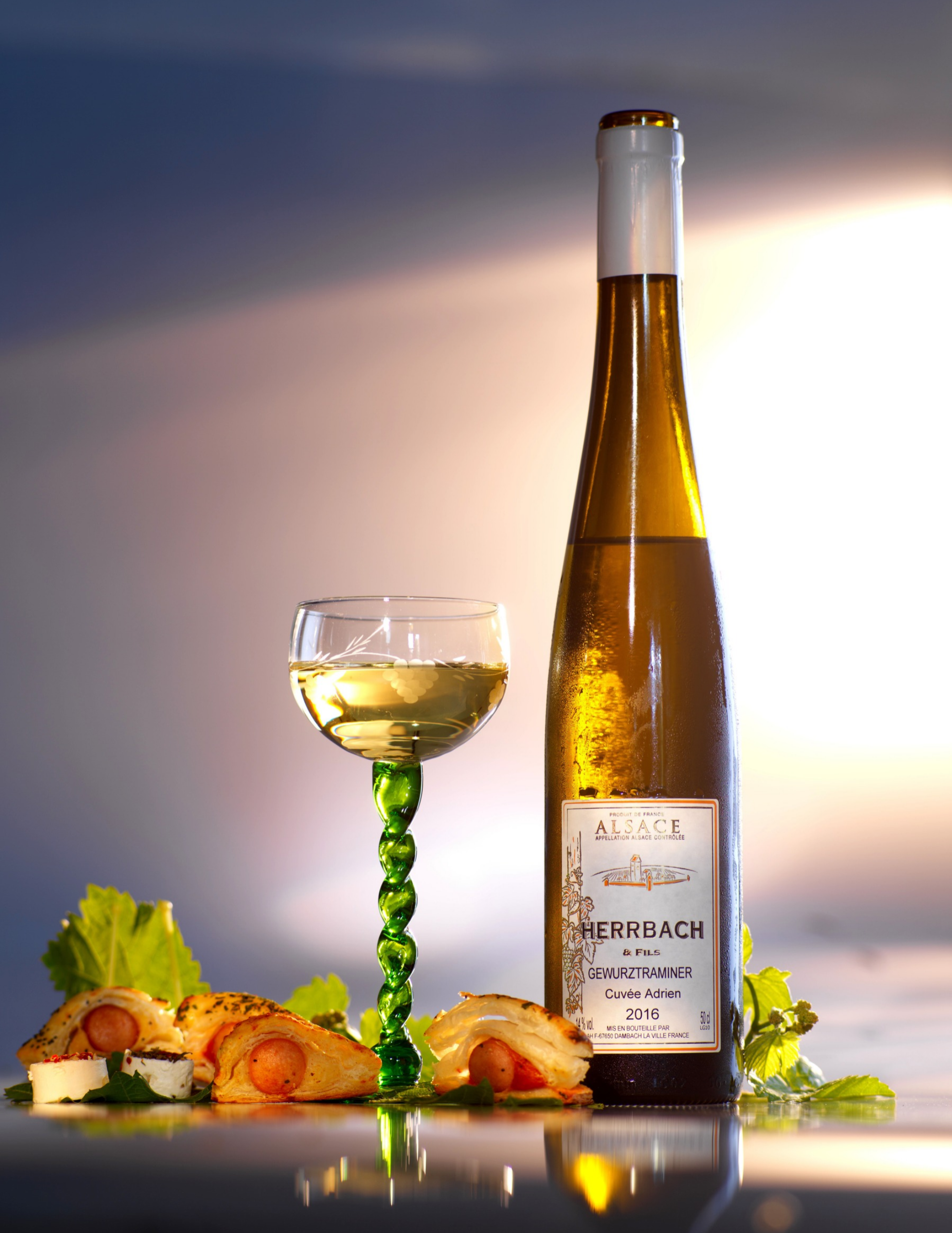 gewurztraminer-alsace-vin-blanc-gastronomie Bouteille de Gewurztraminer Herrbach et Fils d'Alsace, accompagnée d'un verre de vin blanc et de bouchées apéritives.