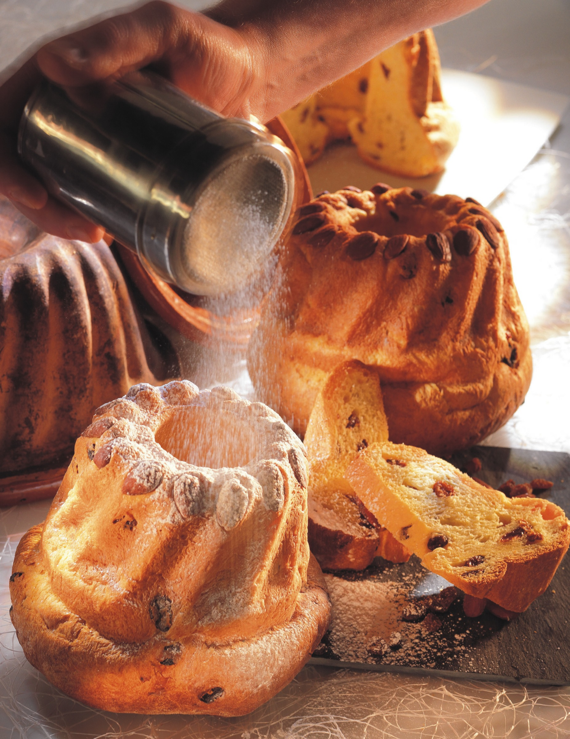 kougelhopf-traditionnel-alsacien Kougelhopfs alsaciens traditionnels saupoudrés de sucre glace, accompagnés de tranches de brioche aux raisins.