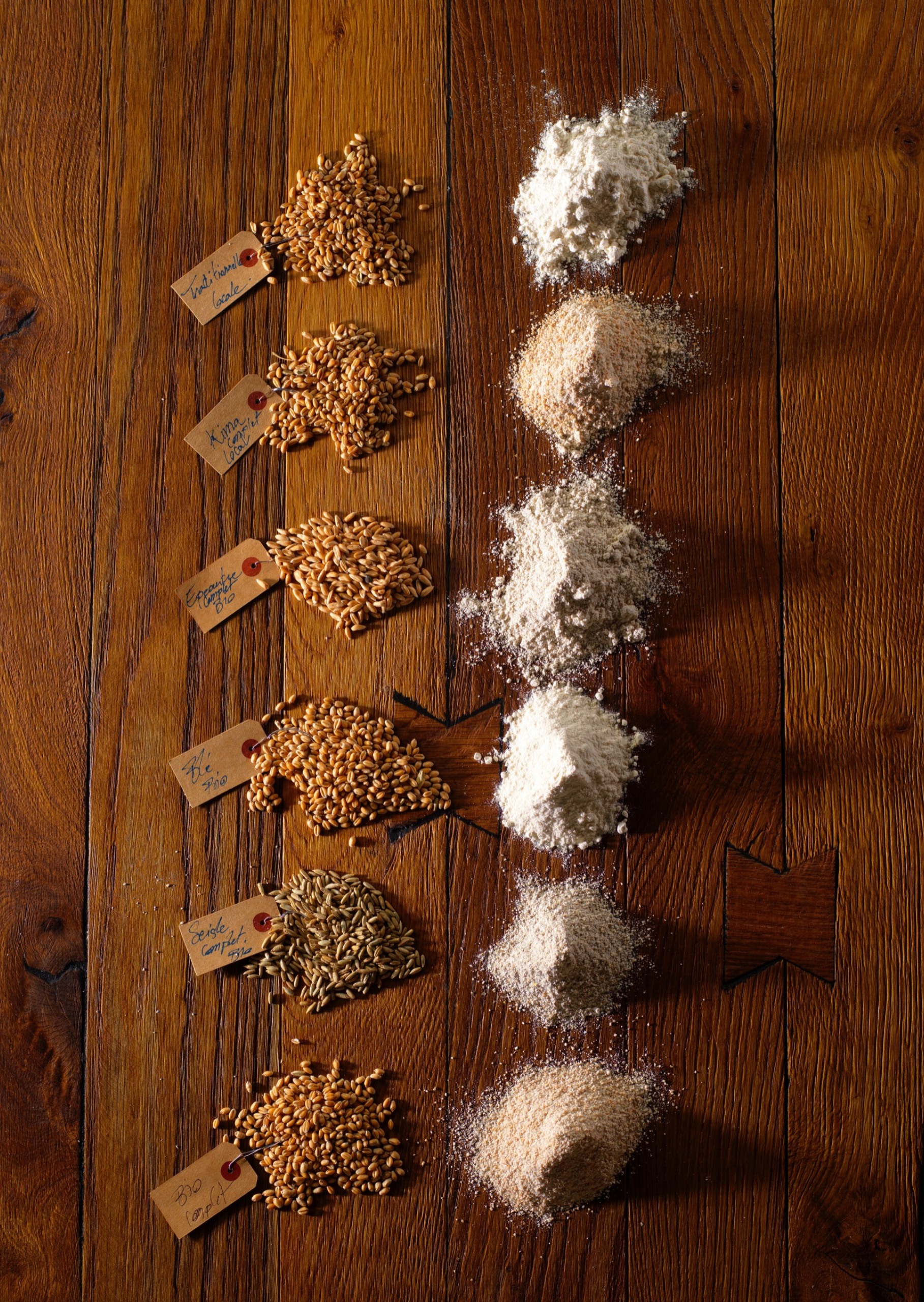 photographe-culinaire-cereales-farines-alsace Photographie professionnelle de différentes variétés de céréales et de farines disposées sur une table en bois, réalisée par Studio Pygmalion.